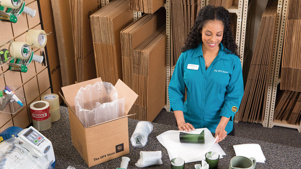 Employee wrapping and packing a glass for shipping