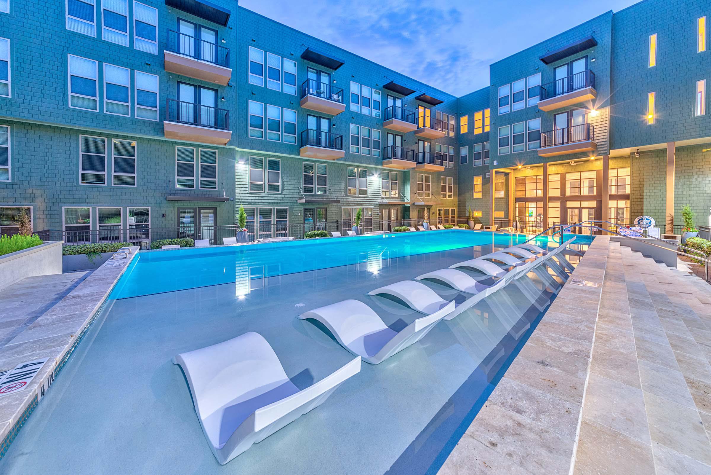 Flats side pool with in-water loungers at twilight