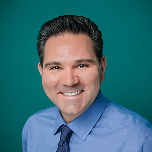 Male doctor in white coat smiling for professional headshot.