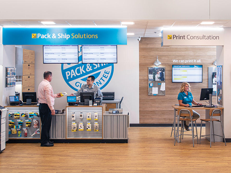 Interior of a The UPS Store location, with a customer completing a transaction at the register