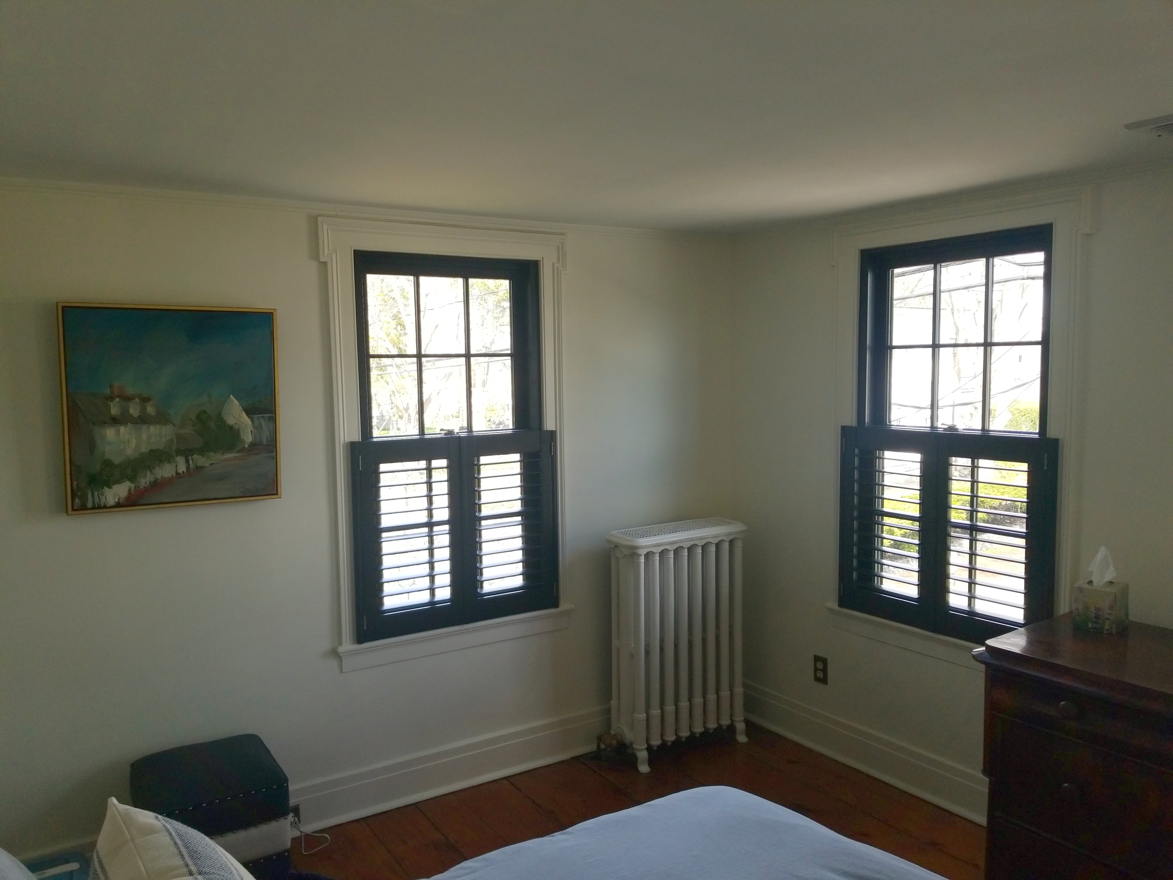 Black cafe shutters match black window frames along with antique brass shutter hardware in Essex, CT.