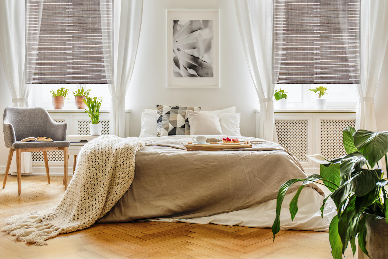 Woven wood shades and sheer drapes pair perfectly to elevate this bedroom. With a perfect contrast in color, pattern, and texture, this space has a balanced and calming feel that will make you want to lounge around all morning.