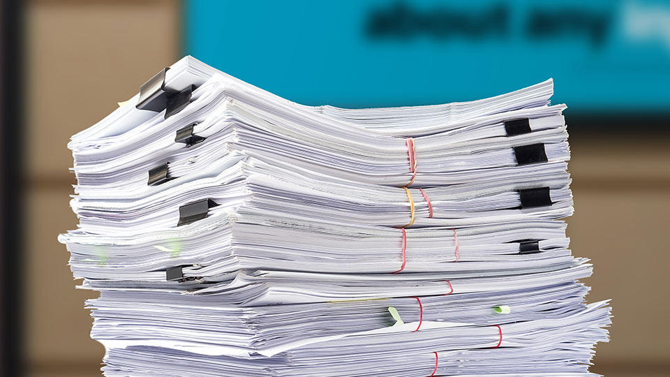 a stack of documents secured with paperclips and rubberbands