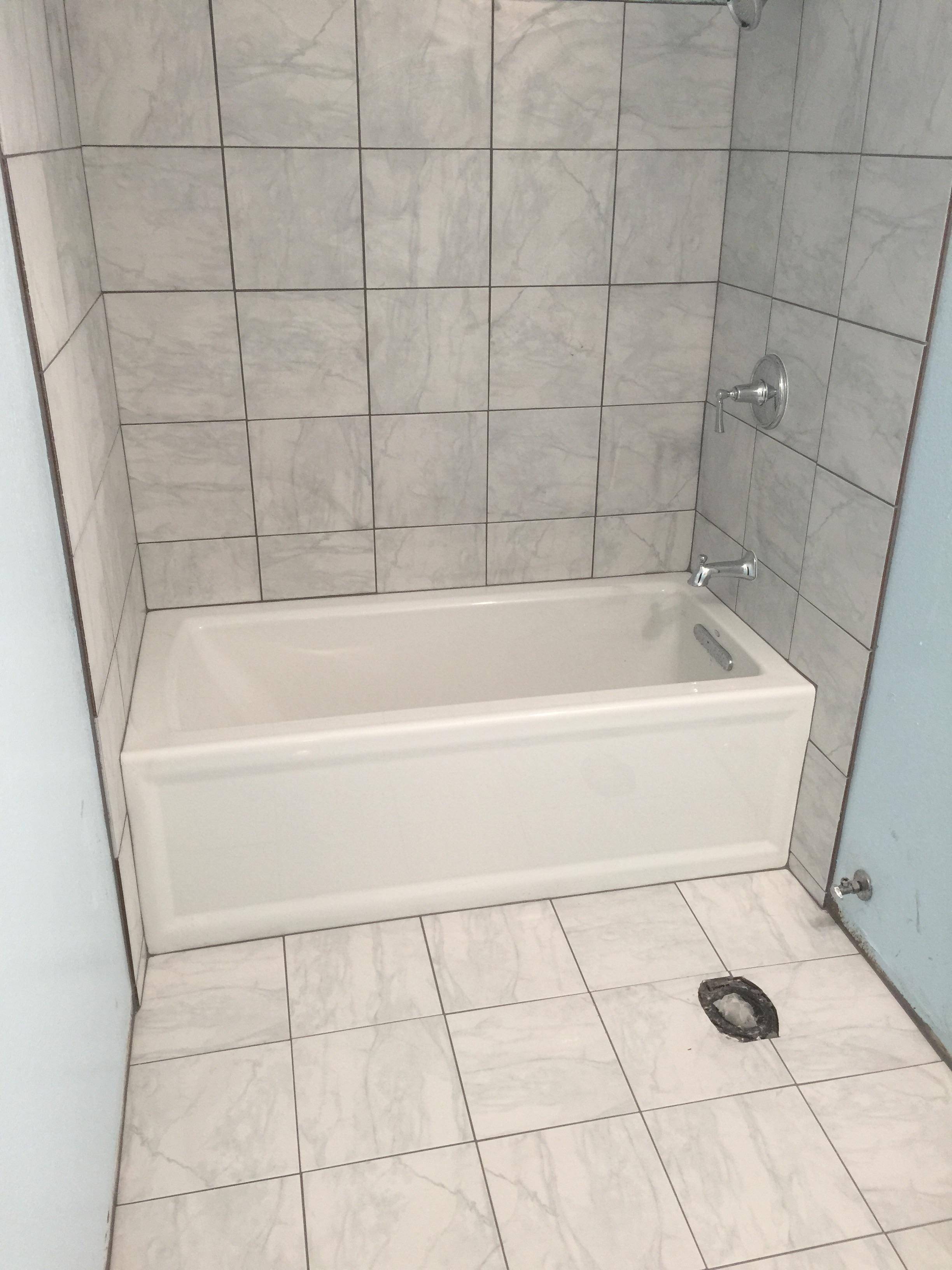 installed kohler bathtub and kohler shower valve fixtures with tile on walls and floor