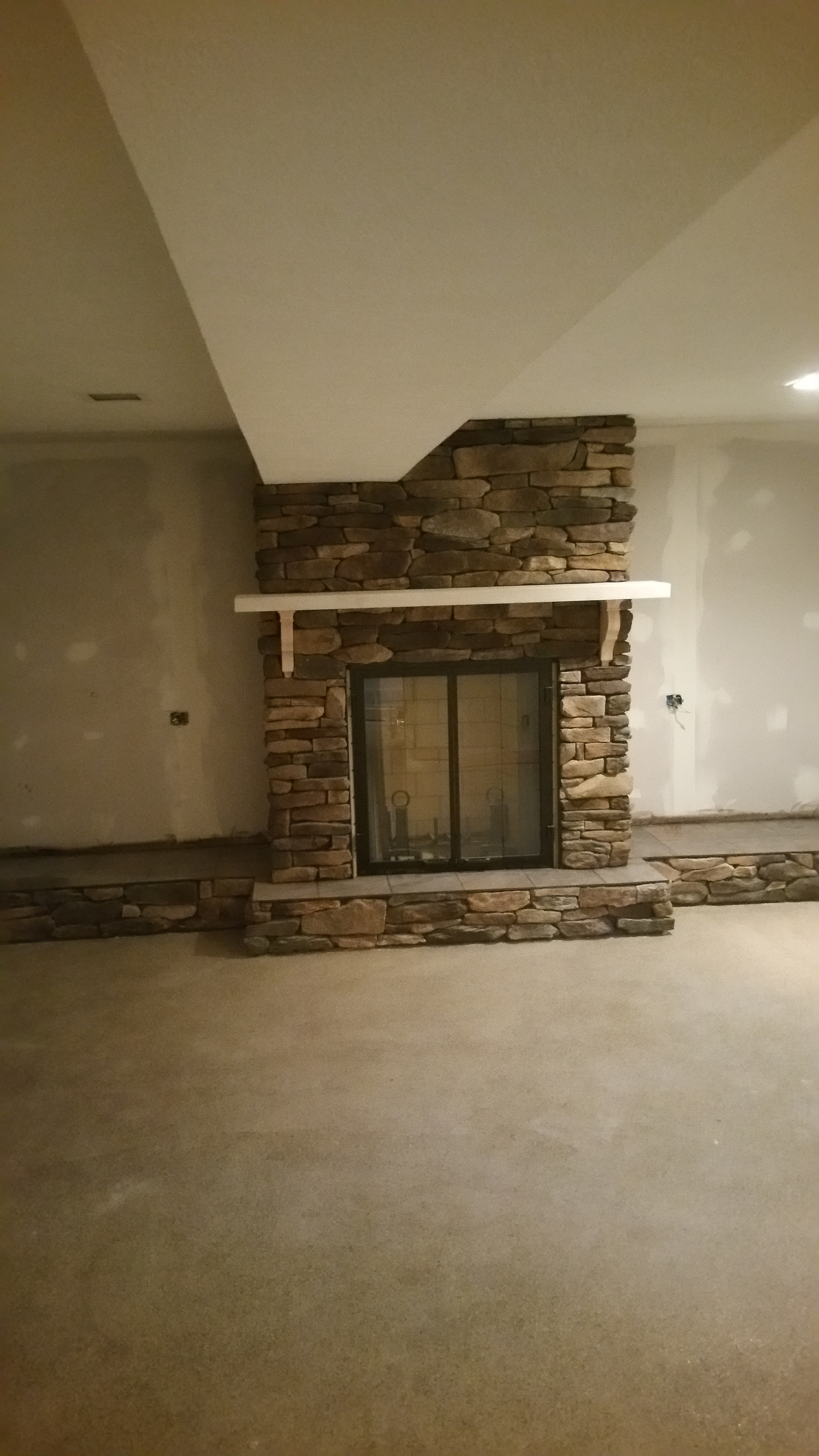 We removed the old Fireplace, and installed a new one. We did a dry stack stone veneer, and a limestone mantel with a tile hearth. While we were there we installed some drywall where the built-in book shelves were on either side if the fireplace.