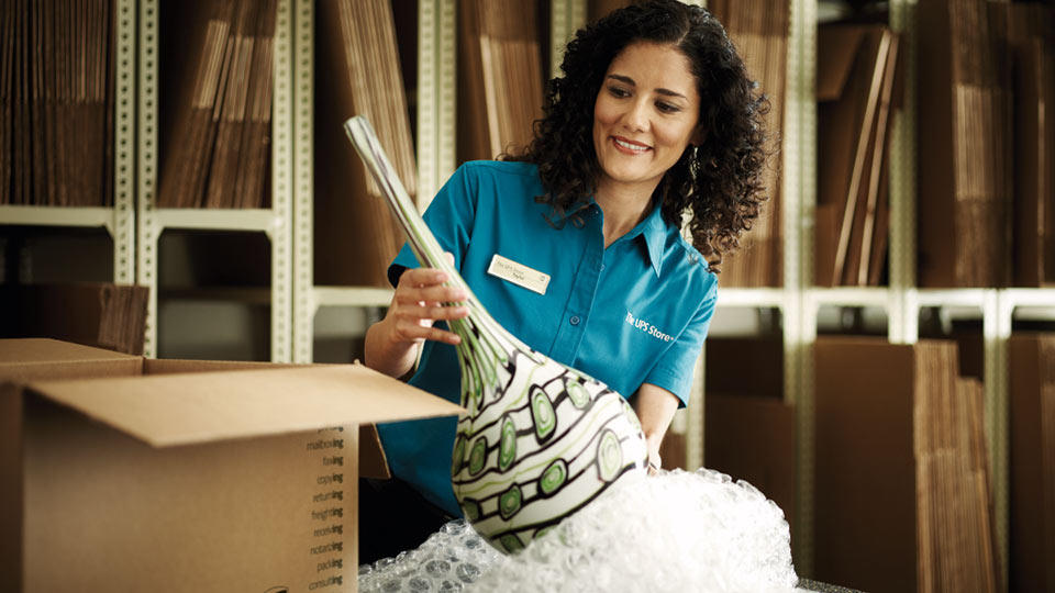 a woman handling an ornate vase for international shipment