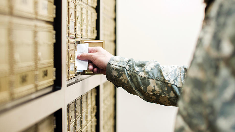 man wearing military uniform getting mail from mailbox