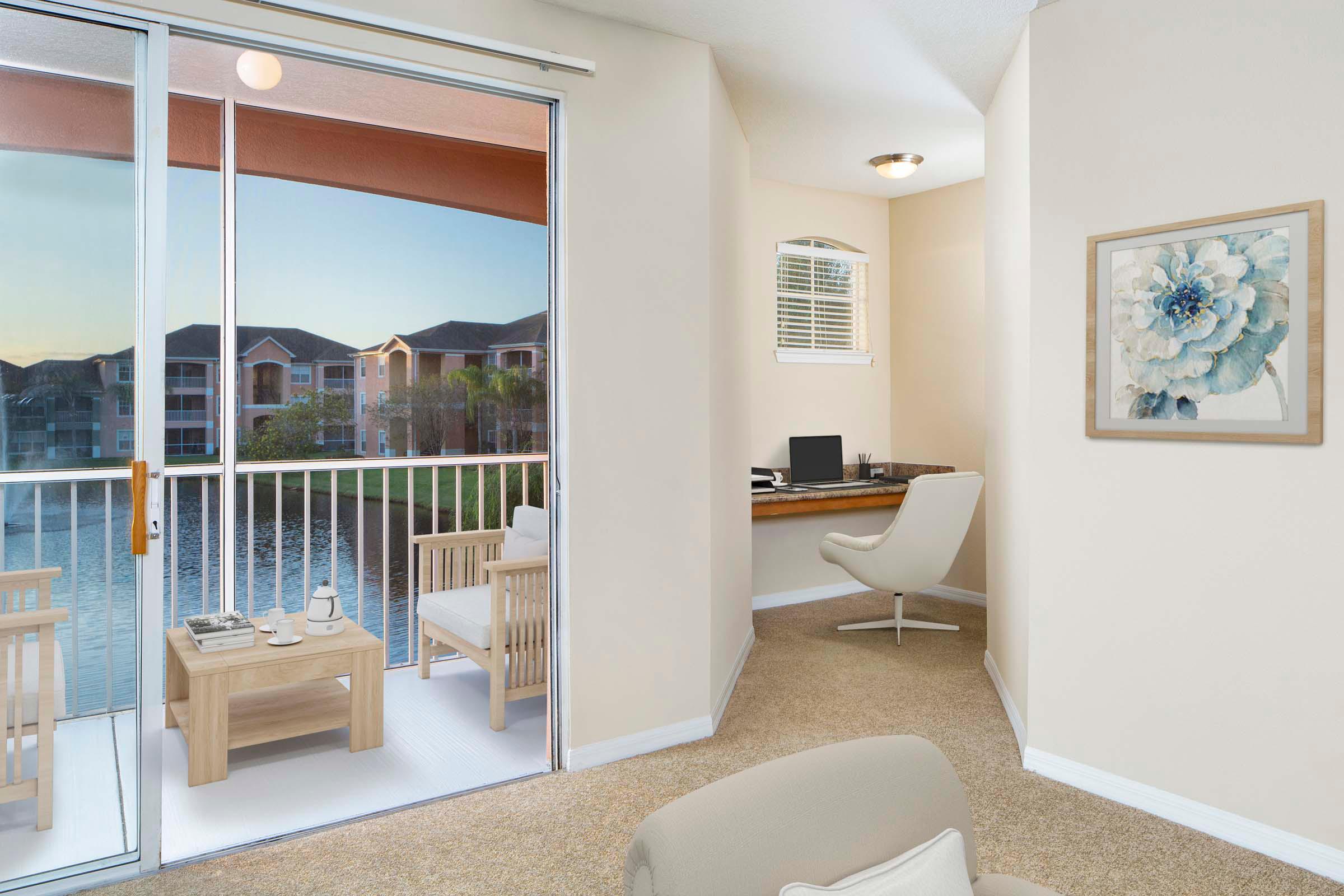 Living area with built in desk alongside sliding glass doors to private balcony