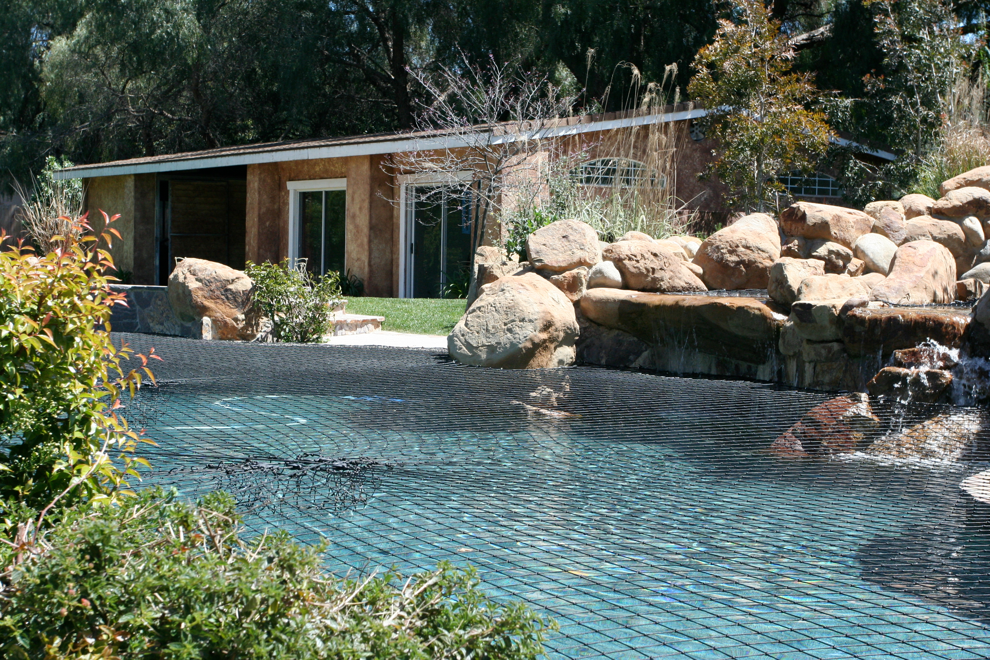 A jet black Katchakid pool safety net works really well as a color option for pool with natural rock features.