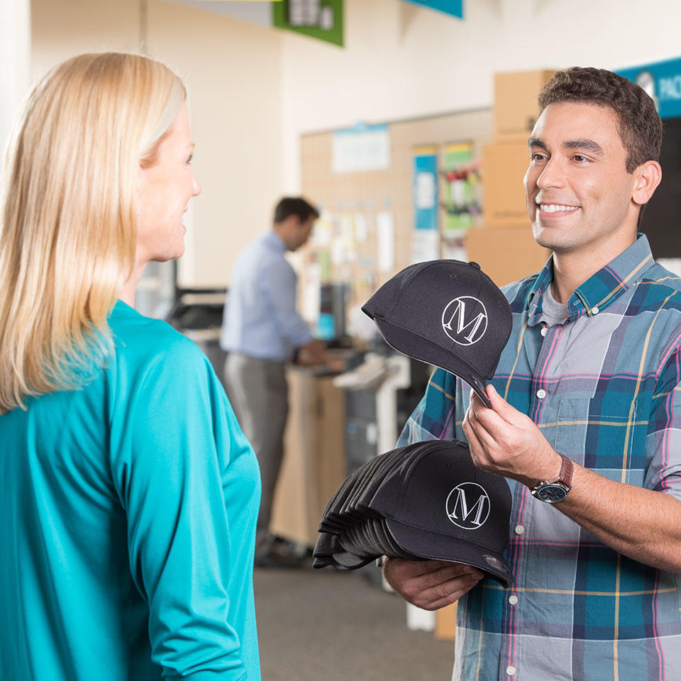 Customer showing The UPS Store franchisee a hat he produces