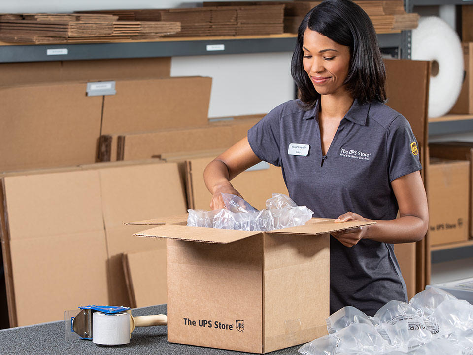 Associate packing an item in a shipping box