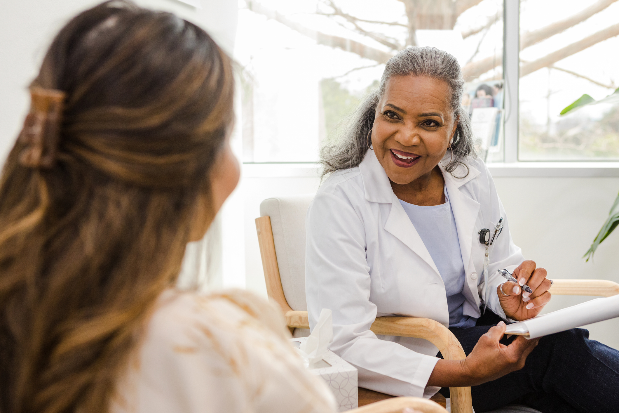 While making notes, the female specialist looks up and smiles at her patient to reassure her that the test results are good news.