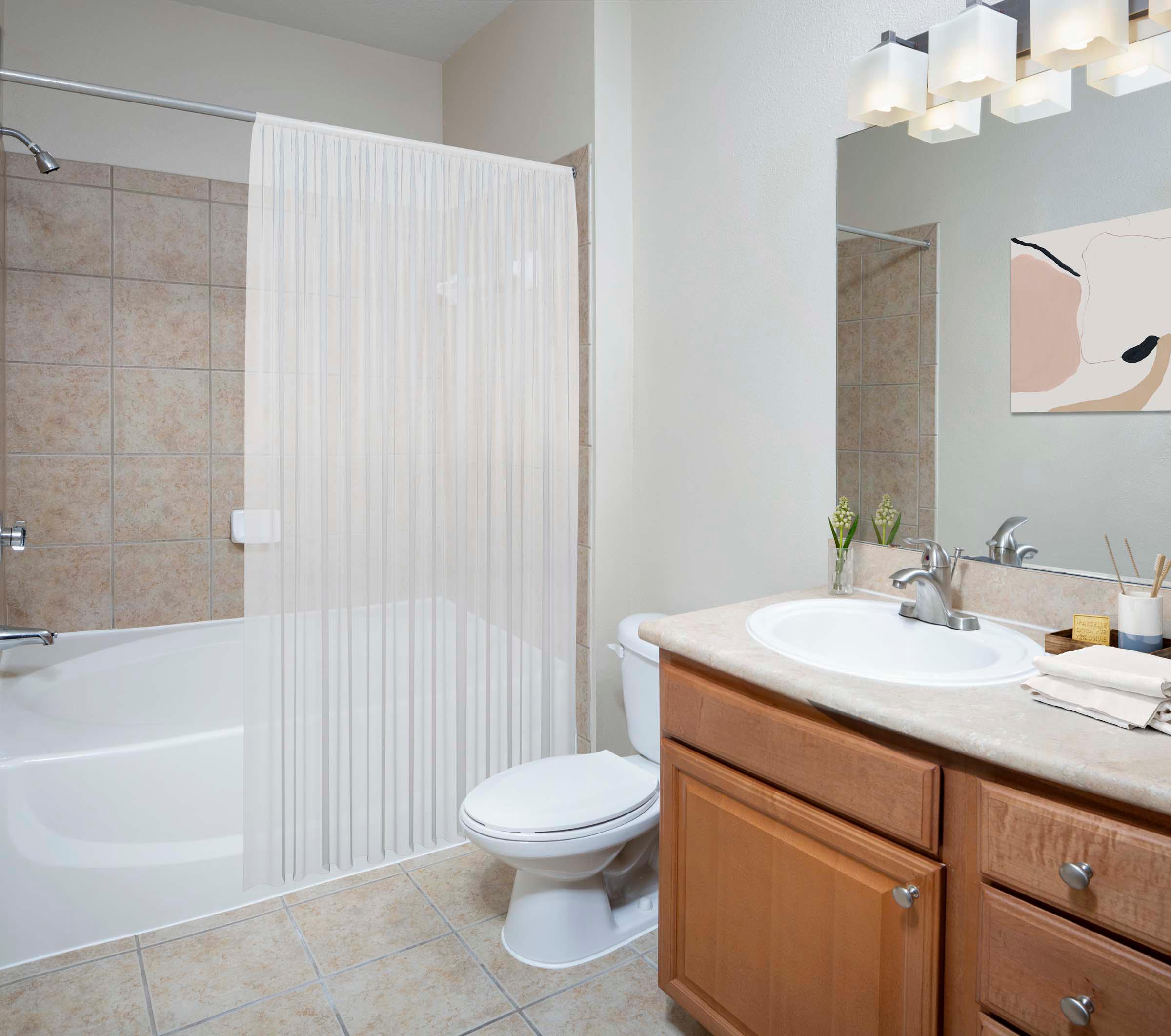 Bathroom with tile flooring bathtub with tile surround and large mirror