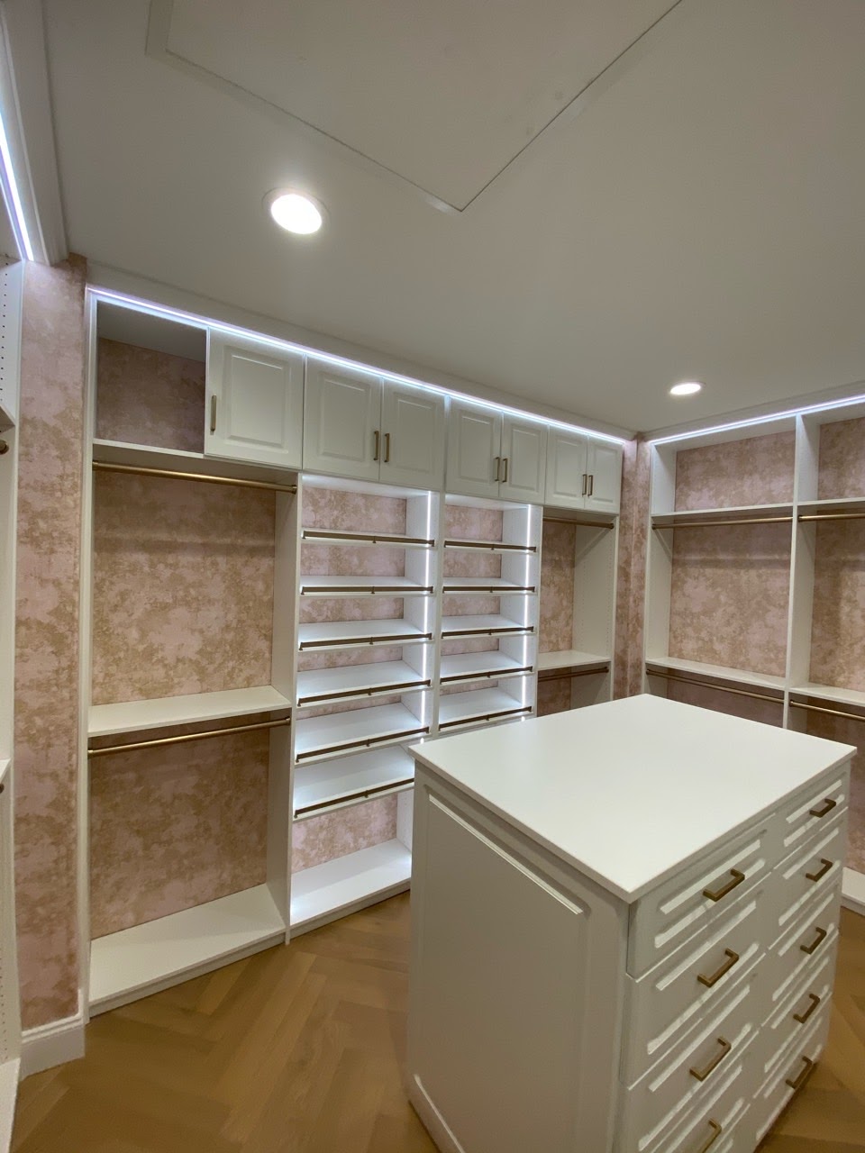 White walk-in closet with lighting and island