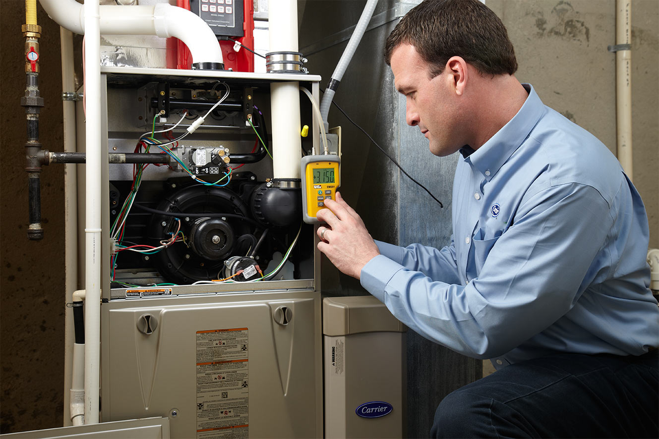 A Carrier dealer performs HVAC maintenance on a furnace