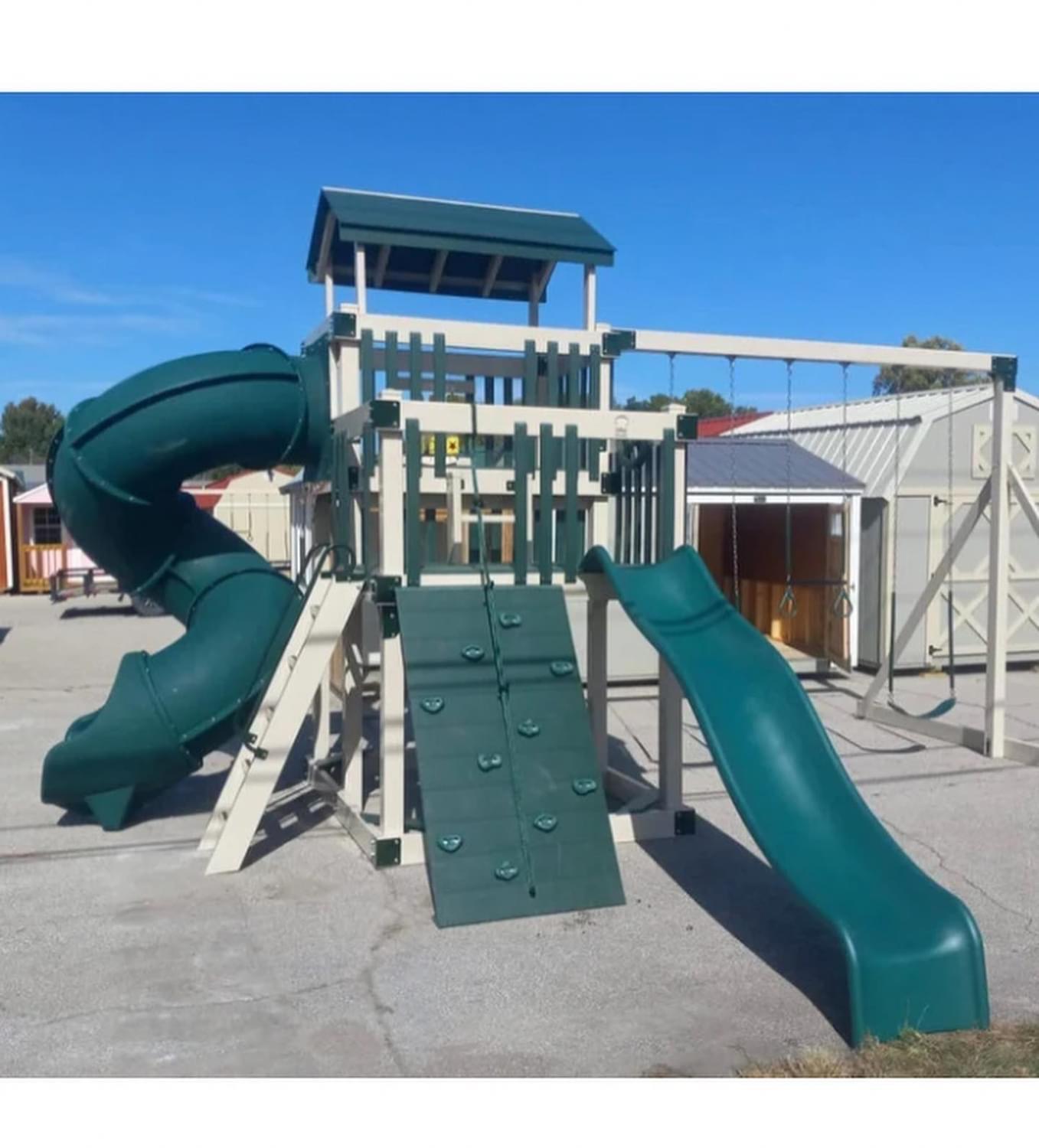 Swing set with tower, roof, rock wall, slides and swings.