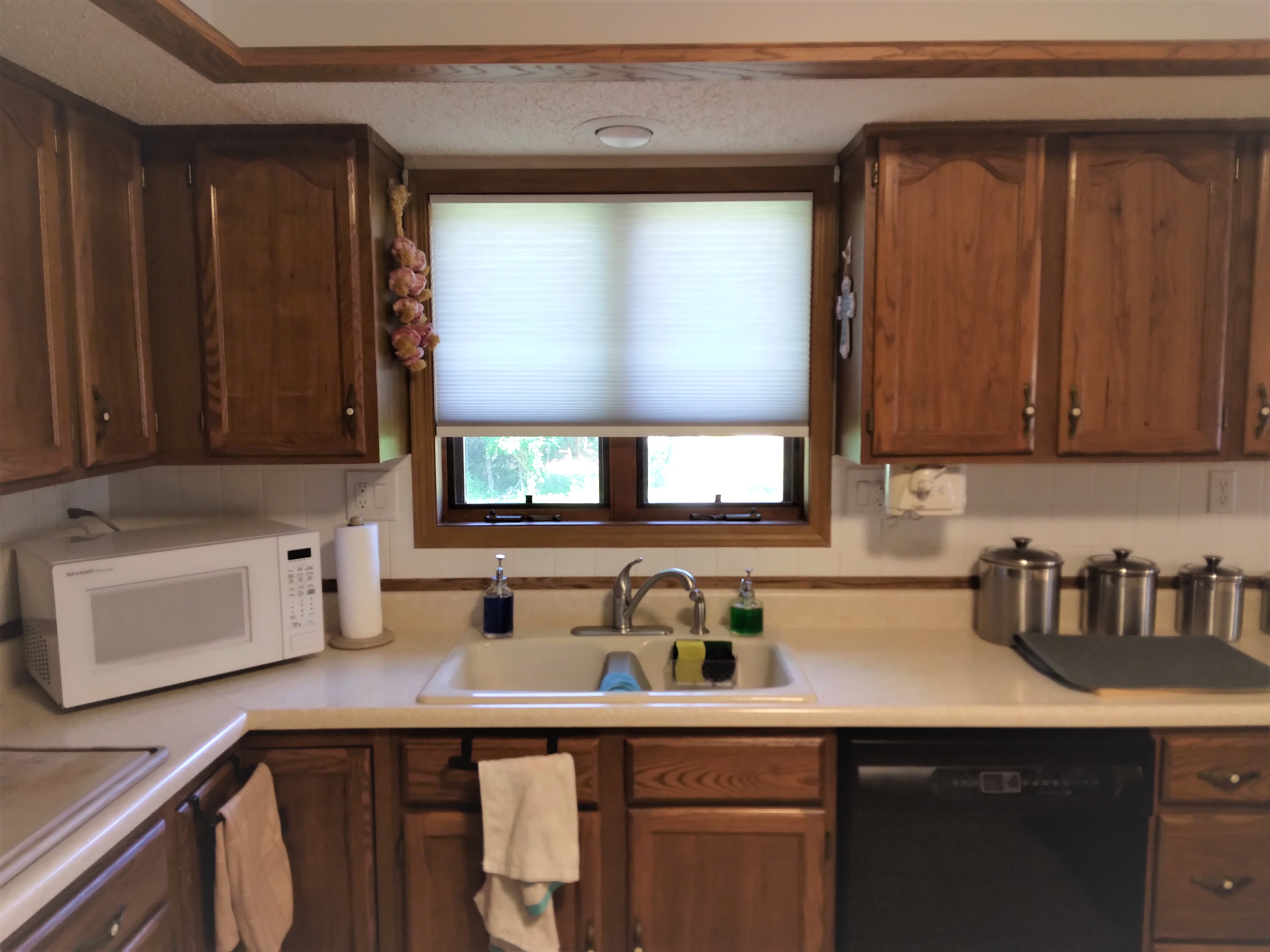 Grey light-filtering cellular shades in Springfield Illinois kitchen.  BudgetBlinds  WindowCoverings  Shades  CellularShades  SpringfieldIllinois