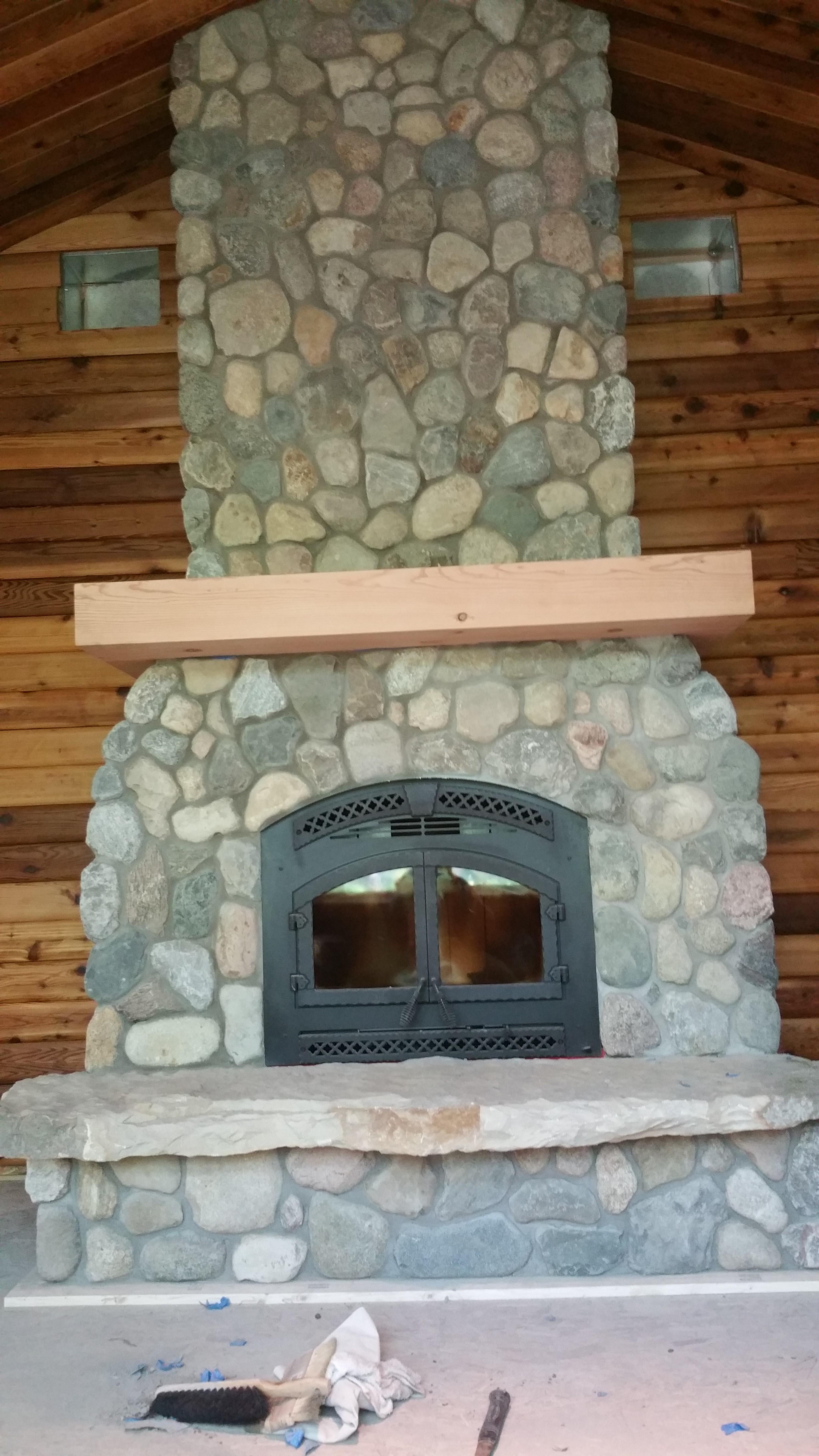 this fireplace is made of Indiana rubble. The hearth came from a creek bed in Green county. We actually hand carved the hearth, no saw cut edges here all natural. The mantel is constructed from structural members from the original log cabin that was on this site as is the logs on the wall behind the fireplace. I think this is the best one we have put together yet!