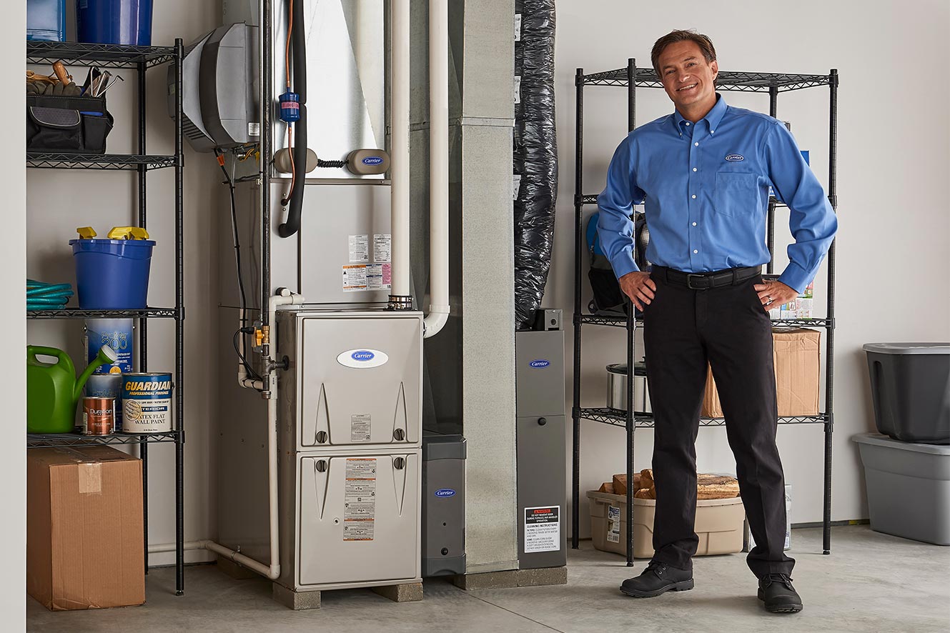 A Carrier dealer standing next to a furnace after a furnace installation