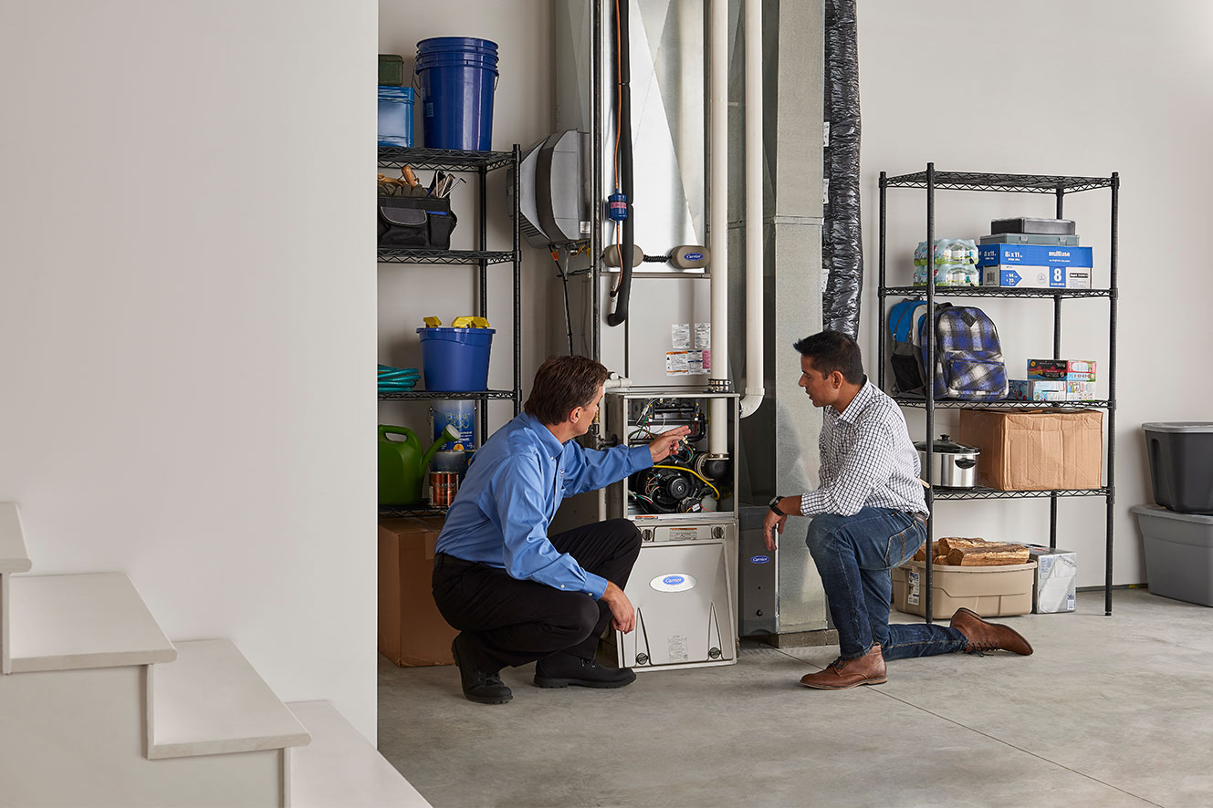 A Carrier dealer show a man the inside of a furnace
