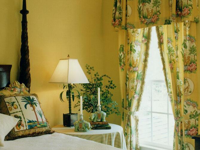 Yellow and green in the drapes and bed pillows create a light and airy room.