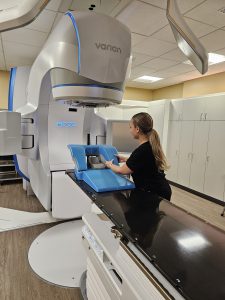 Female medical provider with long ponytail positions specialized medical equipment