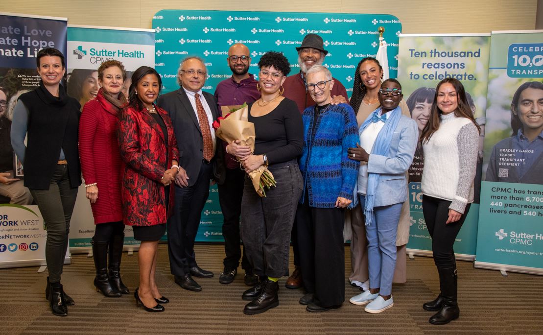 Goldie Williams, a bi-racial liver transplant recipient, holds roses for her Rose Parade send-off event at Sutter CPMC. Williams is surrounded by her hospital care team, including doctors, nurses and care coordinators, as well as her parents and longtime partner.