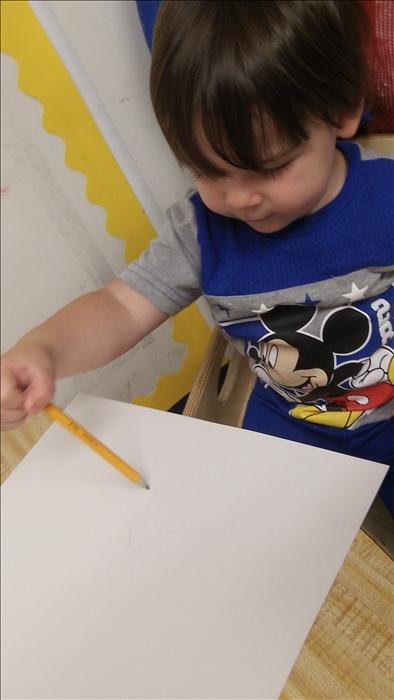 In our toddler class, the children get to experience writing. This allows them to strengthen their small muscles. Here is Alex exploring a pencil.
