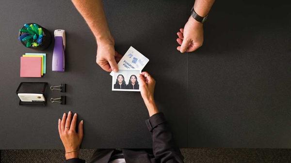 Handing a passport photo across a desk