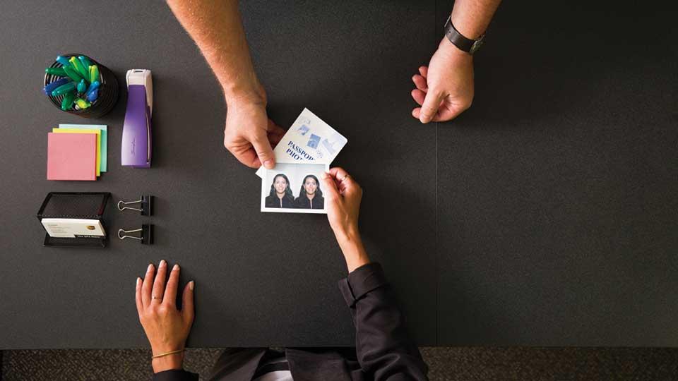 Entrega de una foto de pasaporte por un escritorio