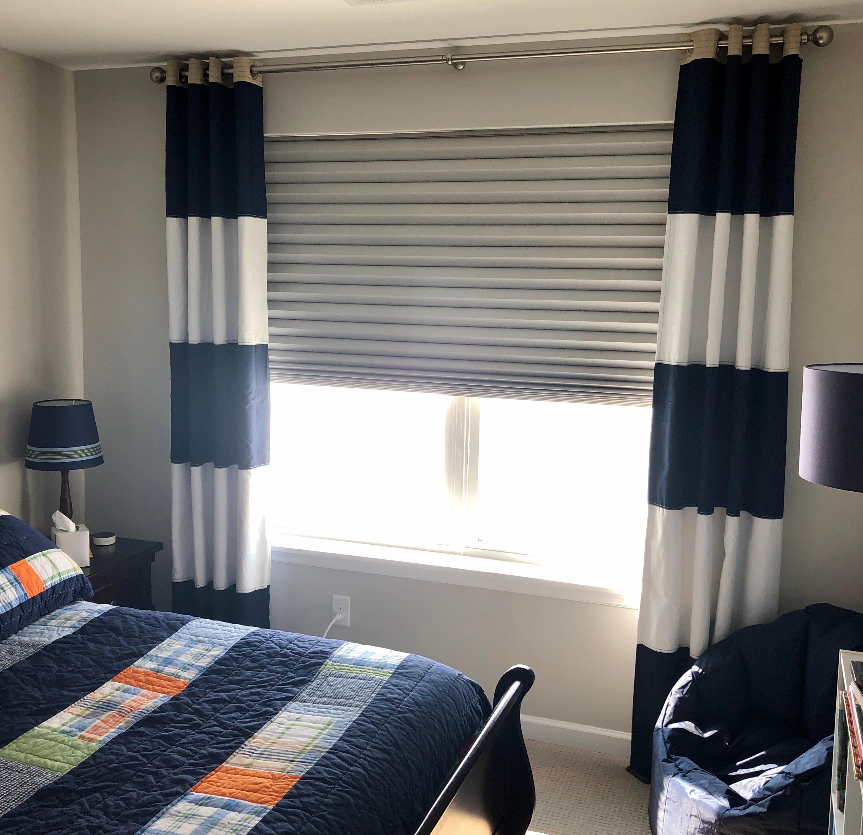We installed a room-darkening shade and nautical-stripe stationary panels to make this child's bedroom window both functional and stylish. The shade operates without cords for child safety.