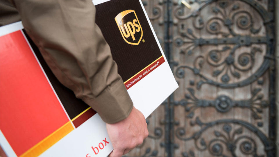 Primer plano del repartidor de UPS parado frente a la puerta