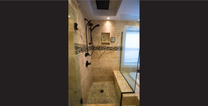 Custom Travertine tile with Mosaic border, Oil Rubbed Bronze fixtures, and custom glass surround
