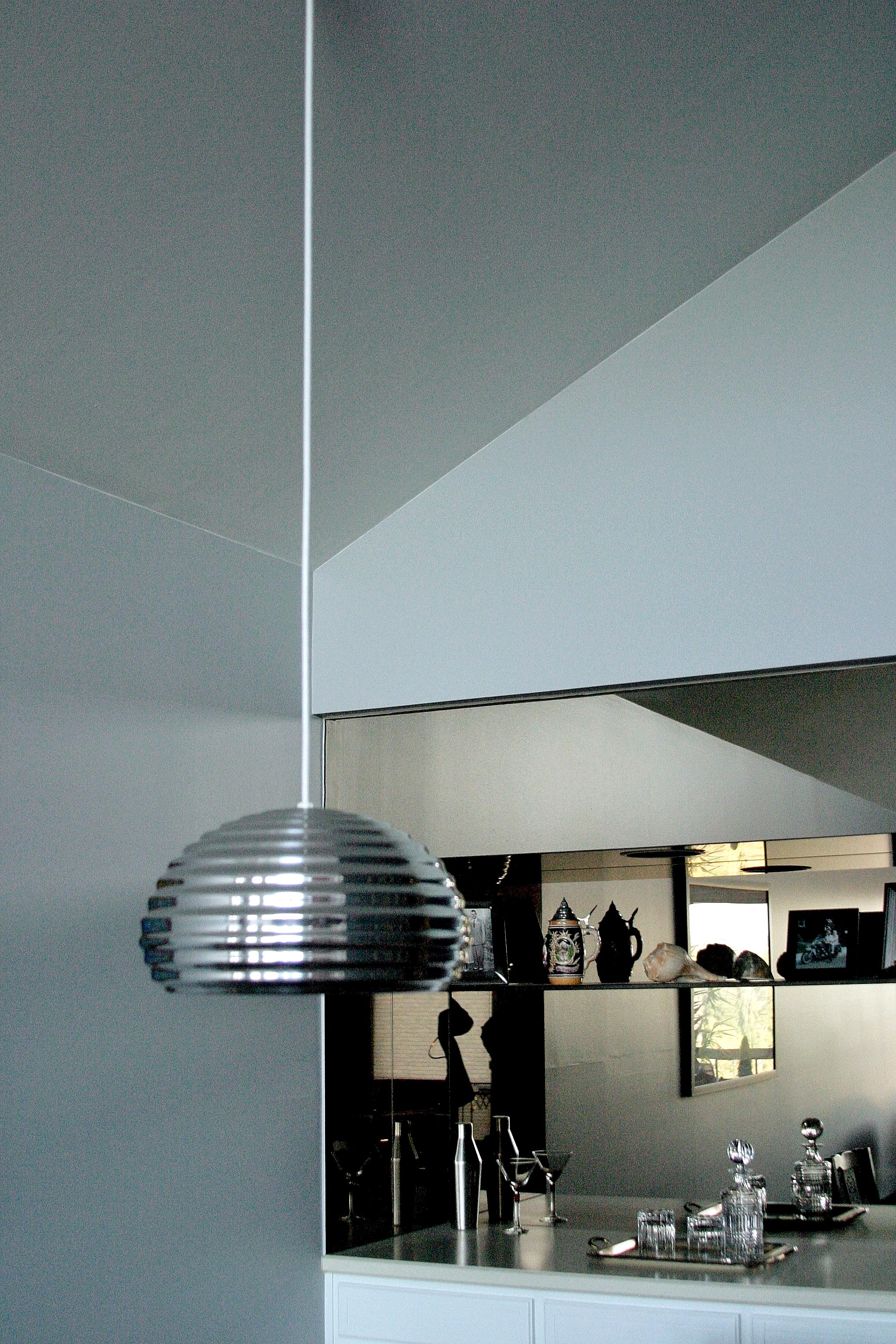 The shiny pendant light reflects the sparkle of the mirrored bar cabinet.