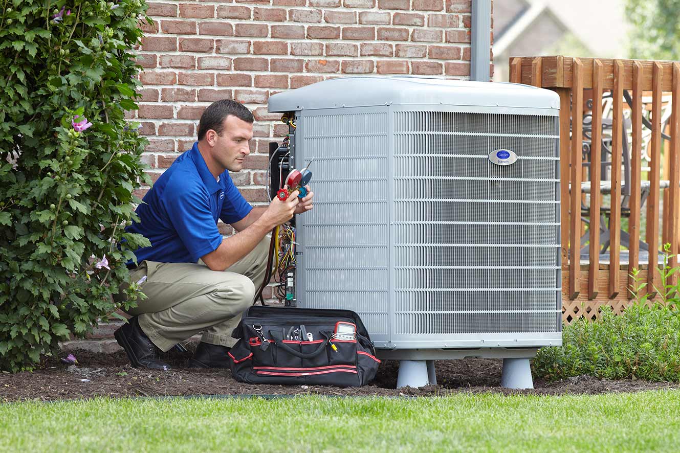 A Carrier dealer checking gauges while installing a heat pump