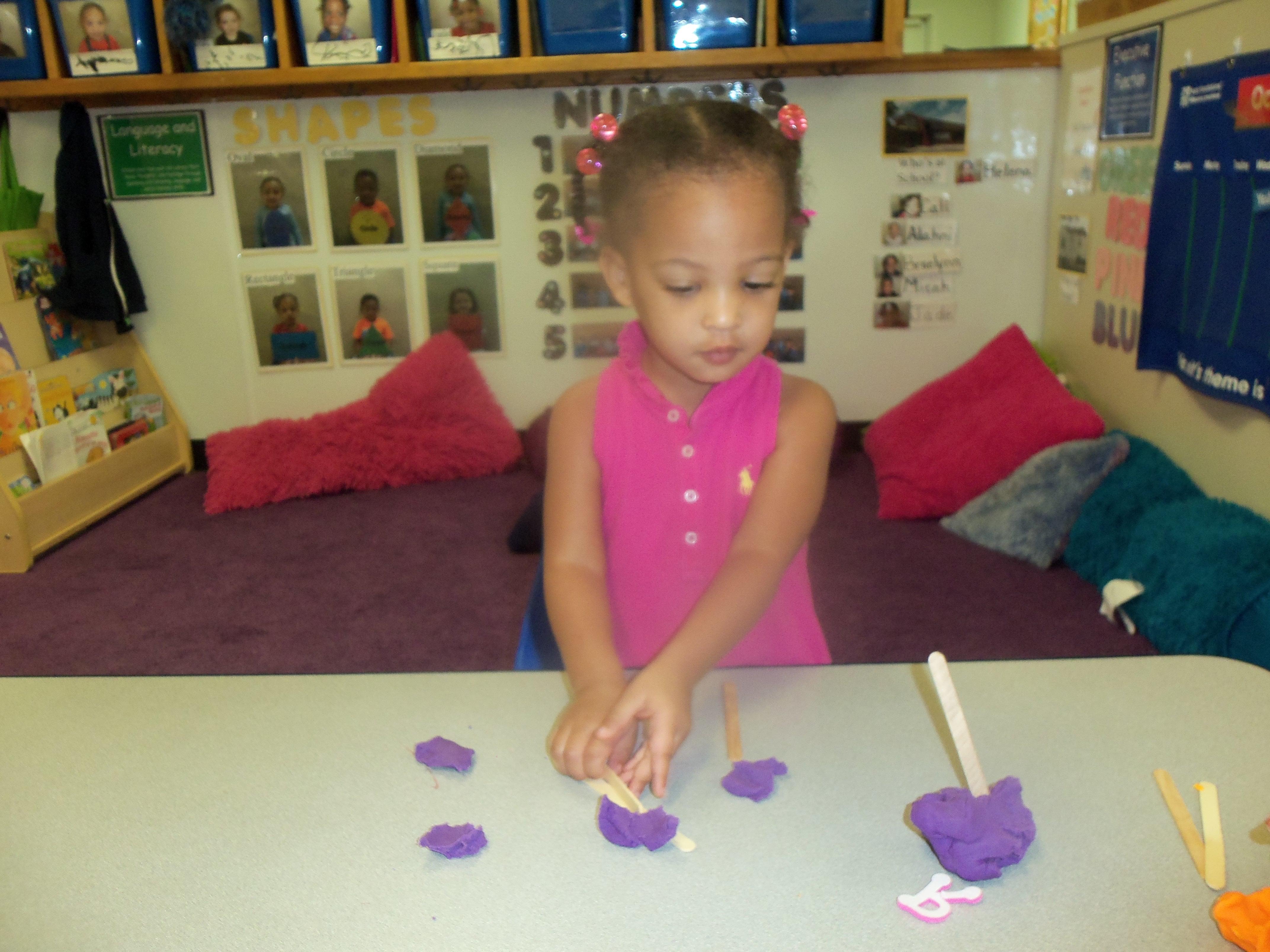 We play with play dough a lot, making all kinds of things! Here we are using popsicle sticks to build a house!