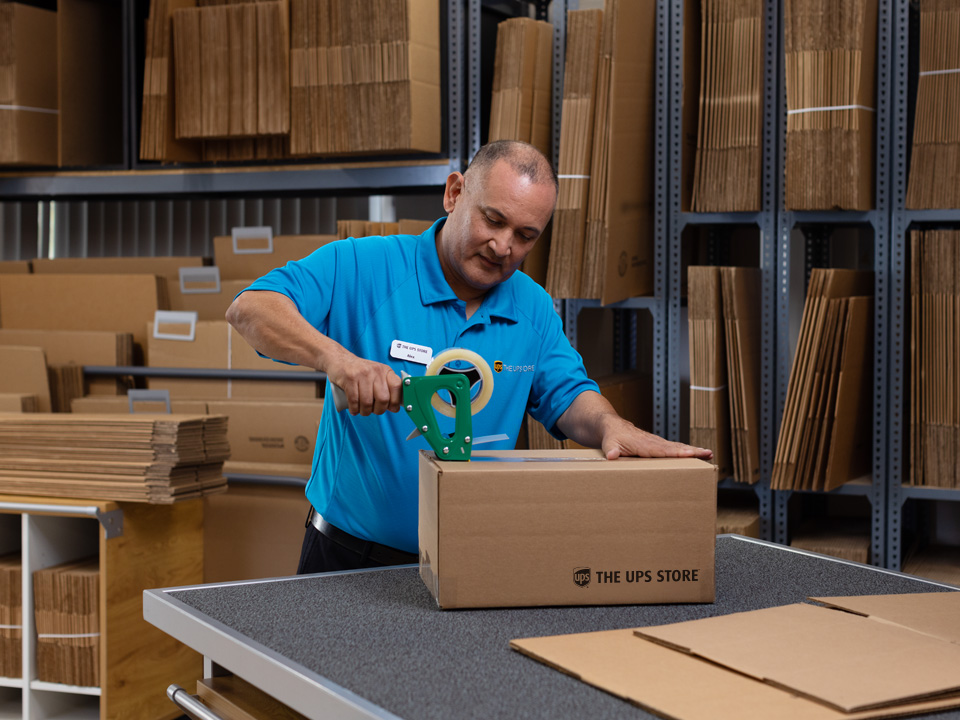 The UPS Store associate taping a box