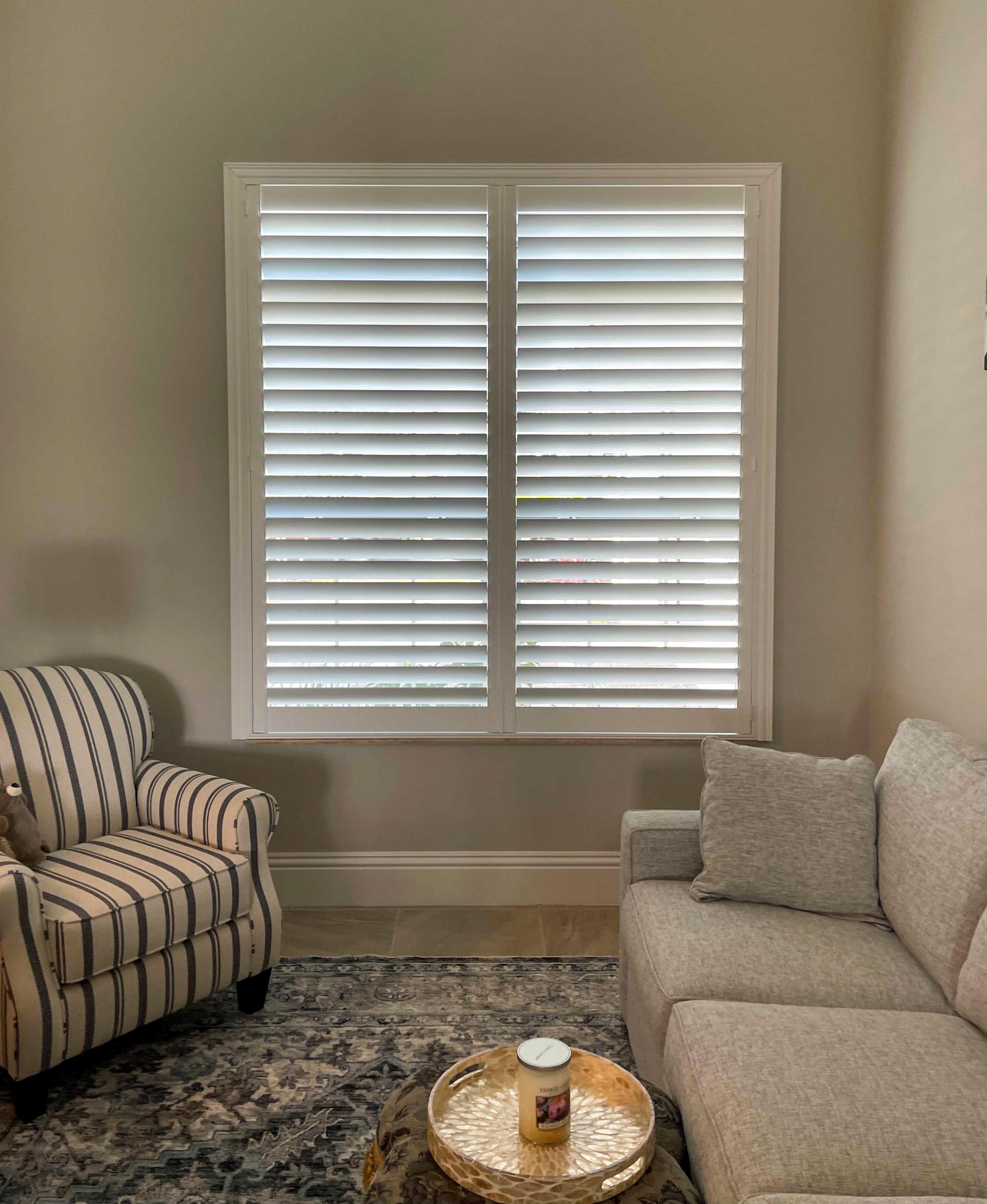 White plantation shutters compliment the pops of subtle blues in this Vero Beach living area.