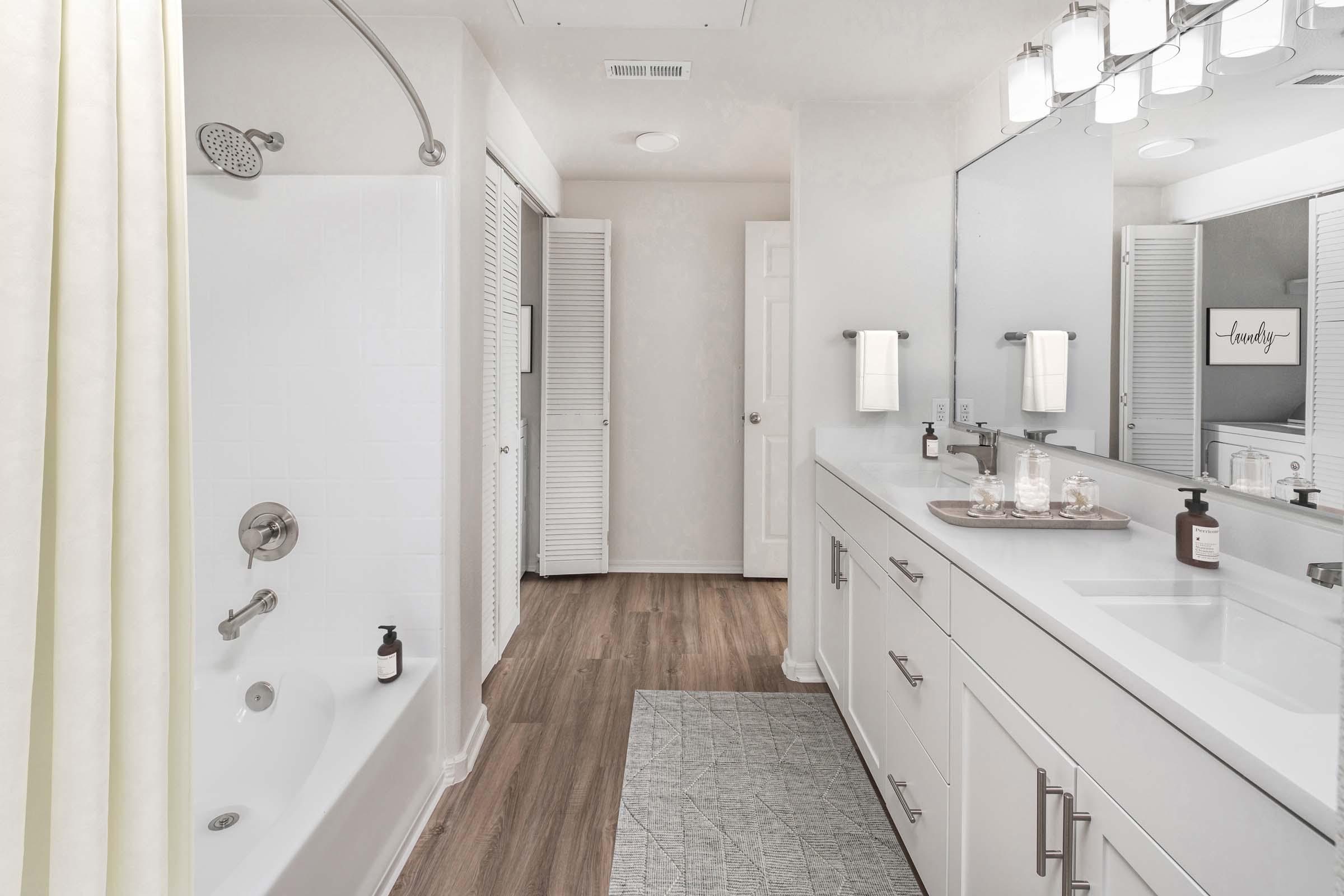 Luxurious bathroom with white quartz countertops, curved shower rod and brushed nickel fixtures