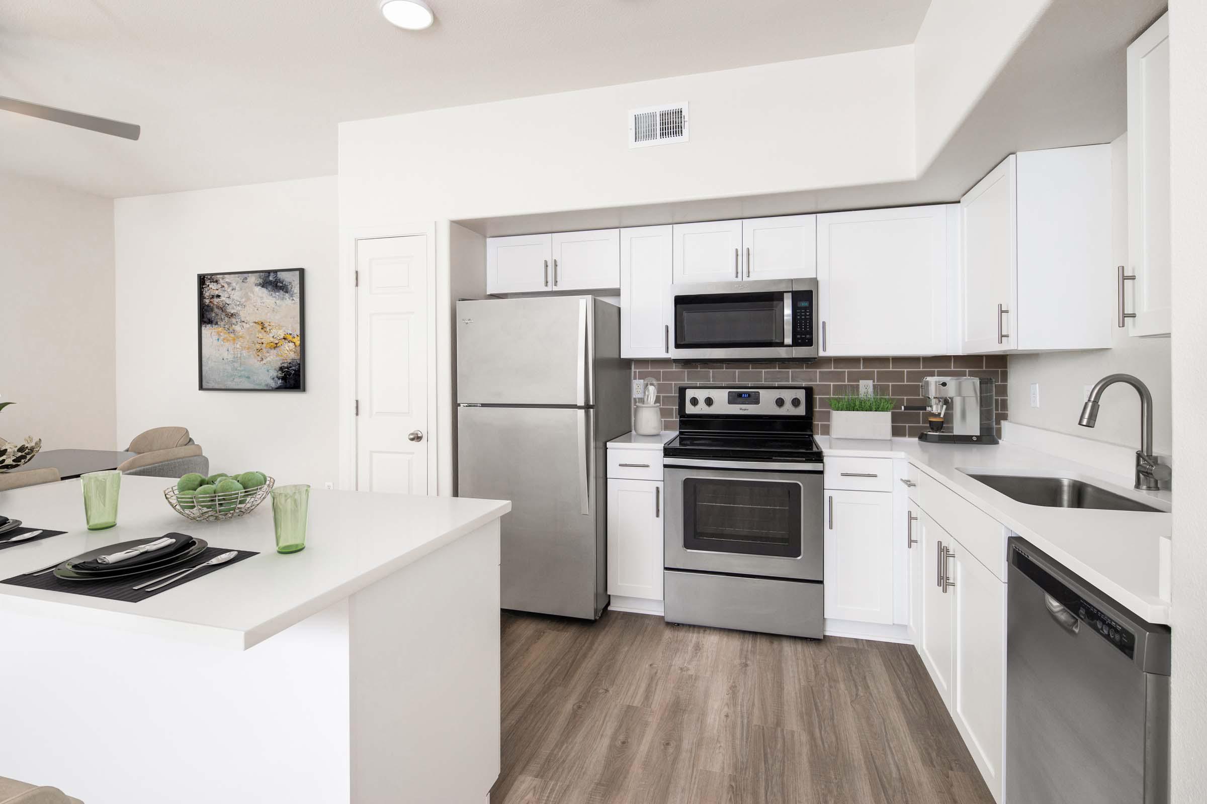 Townhome kitchen with kitchen island, stainless steel appliances, white quartz countertops, subway tile backsplash, and brushed nickel fixtures