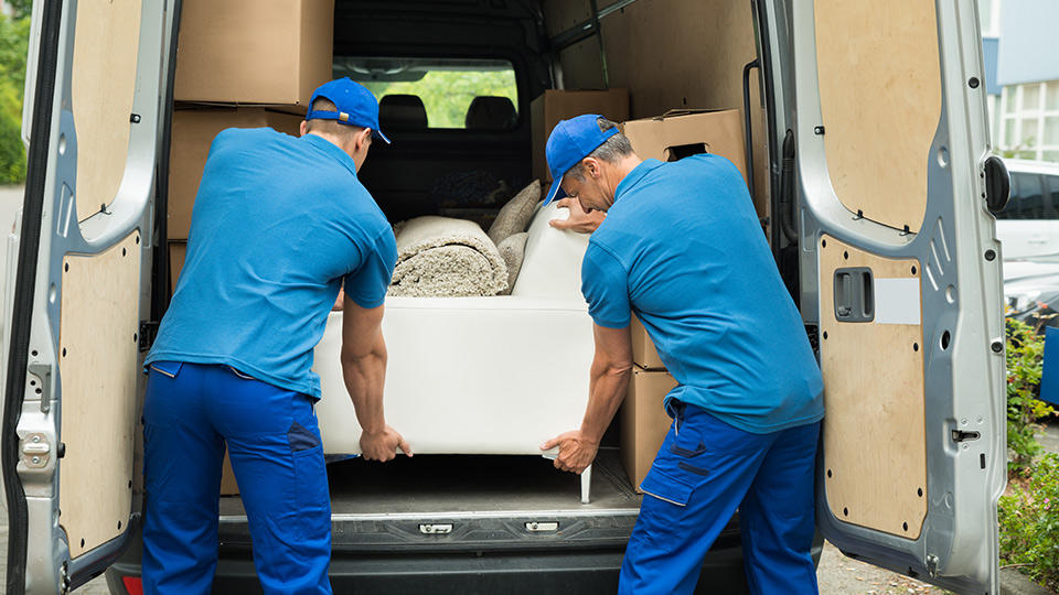 Dos hombres trasladan un sofá pesado.