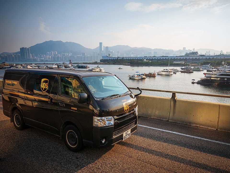 a brown UPS van crosses a bridge over water