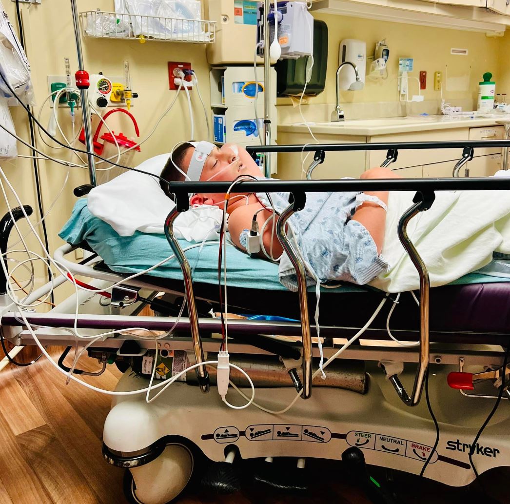 Teenage boy, who is White, lays in a hospital bed with