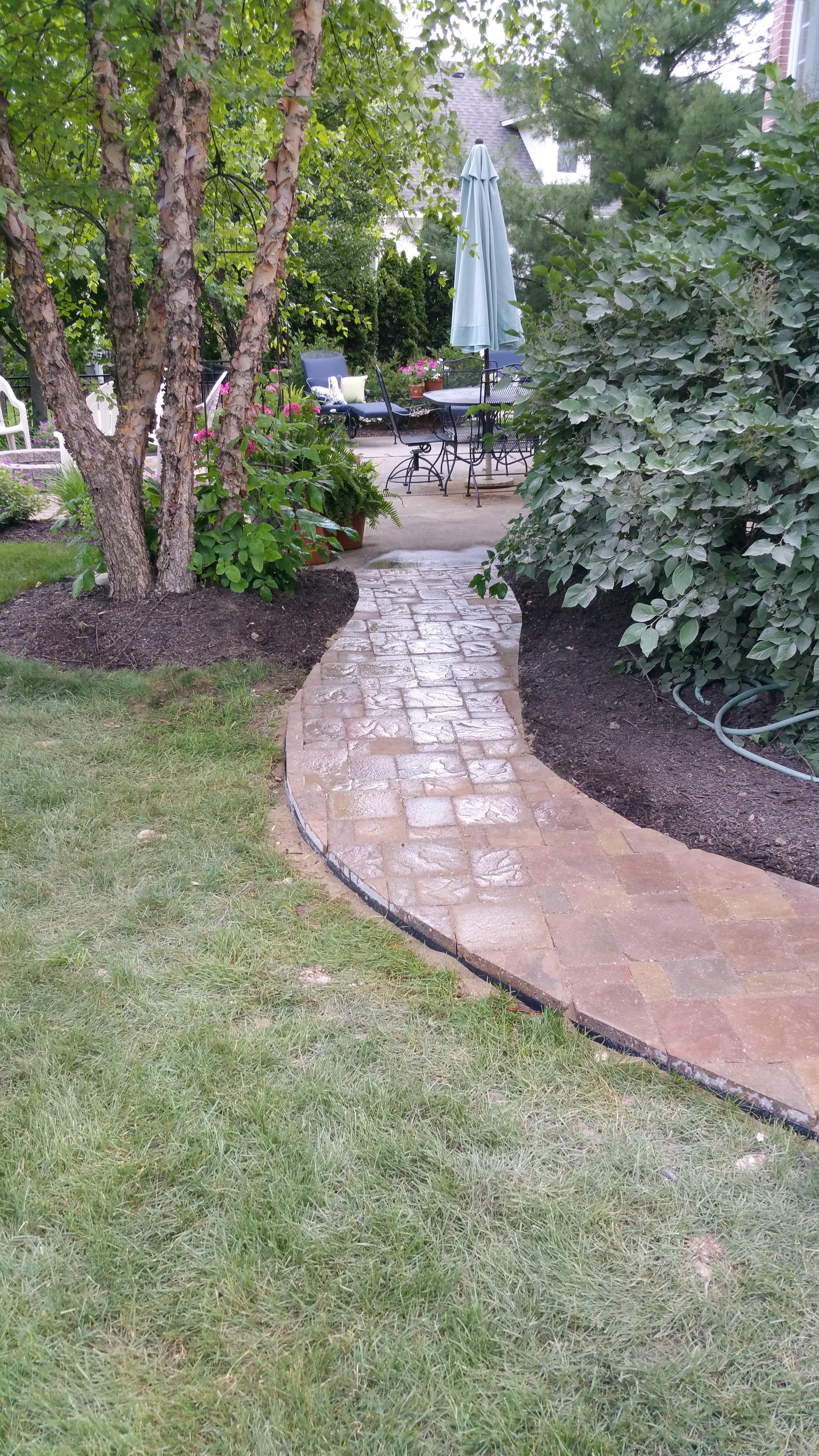 There was no sidewalk here when we got on the job. We cut out the sod and put in this beautiful sidewalk from the drive winding around the flower beds and to the patio in the back yard.