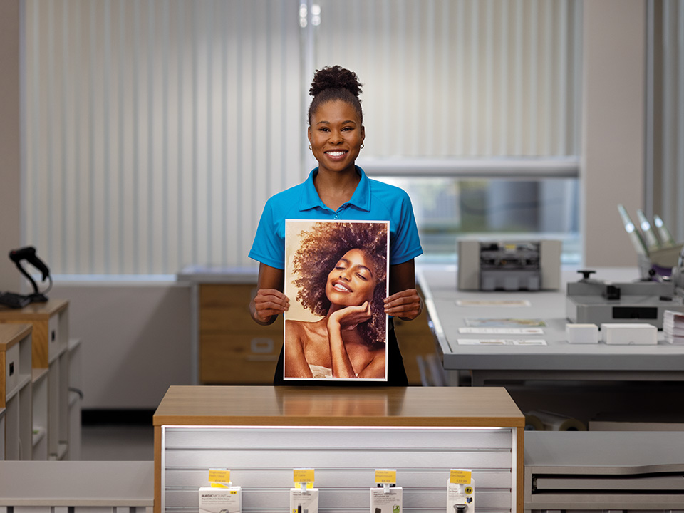 The UPS Store associate holding a large print photo of a woman