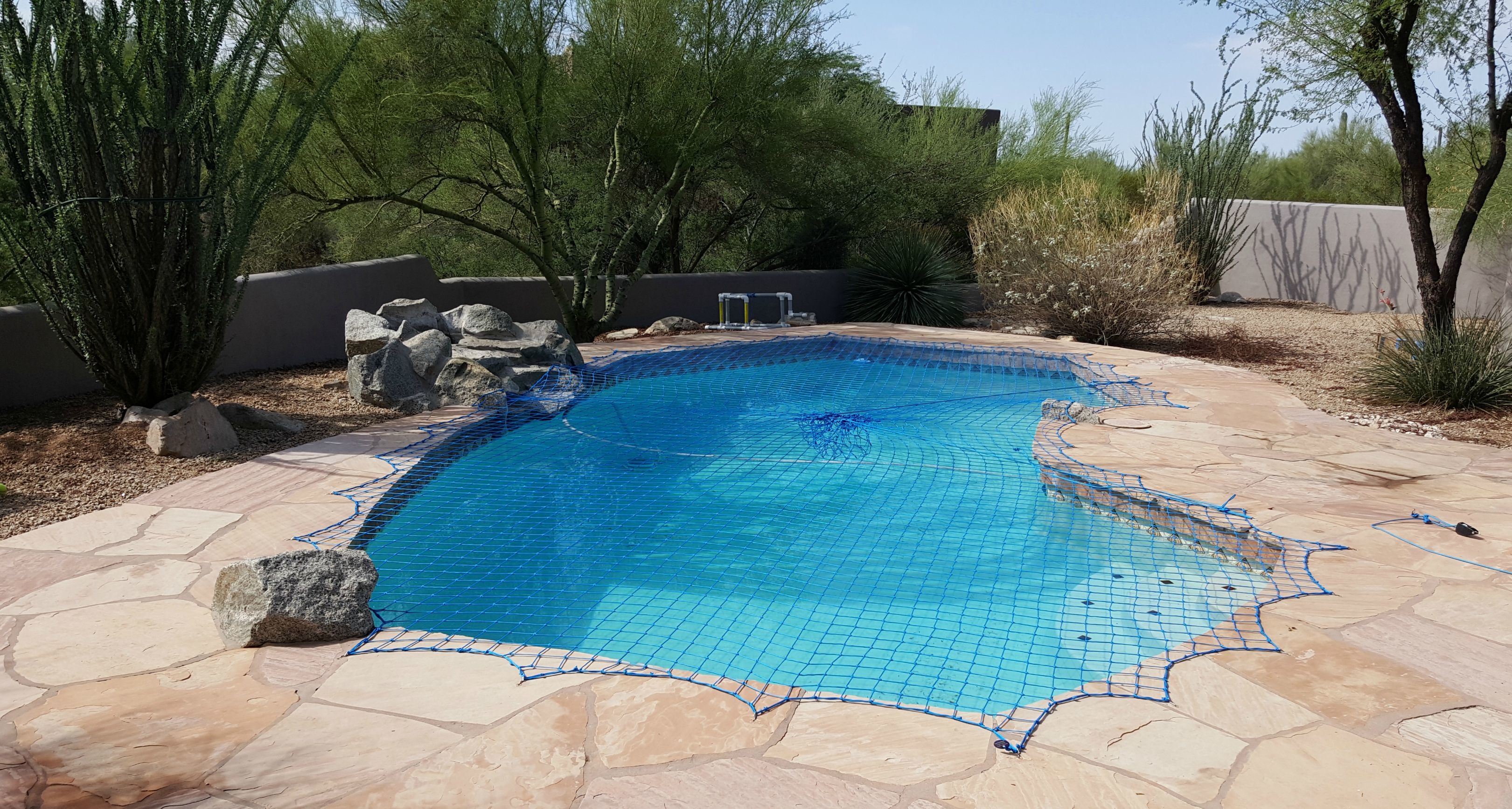 A Katchakid pool safety net cover over an irregular shaped pool.