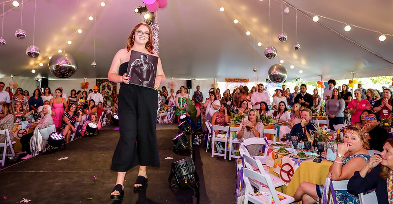 Caucasian woman holds photo of a loved one who died of cancer at a cancer fundraising event called Catwalk For A Cure