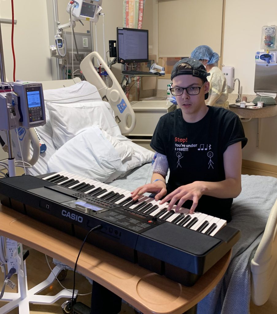 Teen plays a portable keyboard in a hospital room.