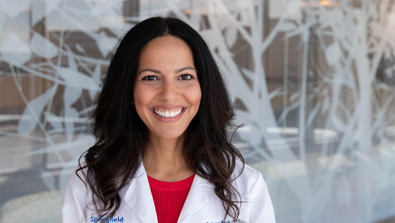 Woman smiling in front of a clear wall with a white tree decal.