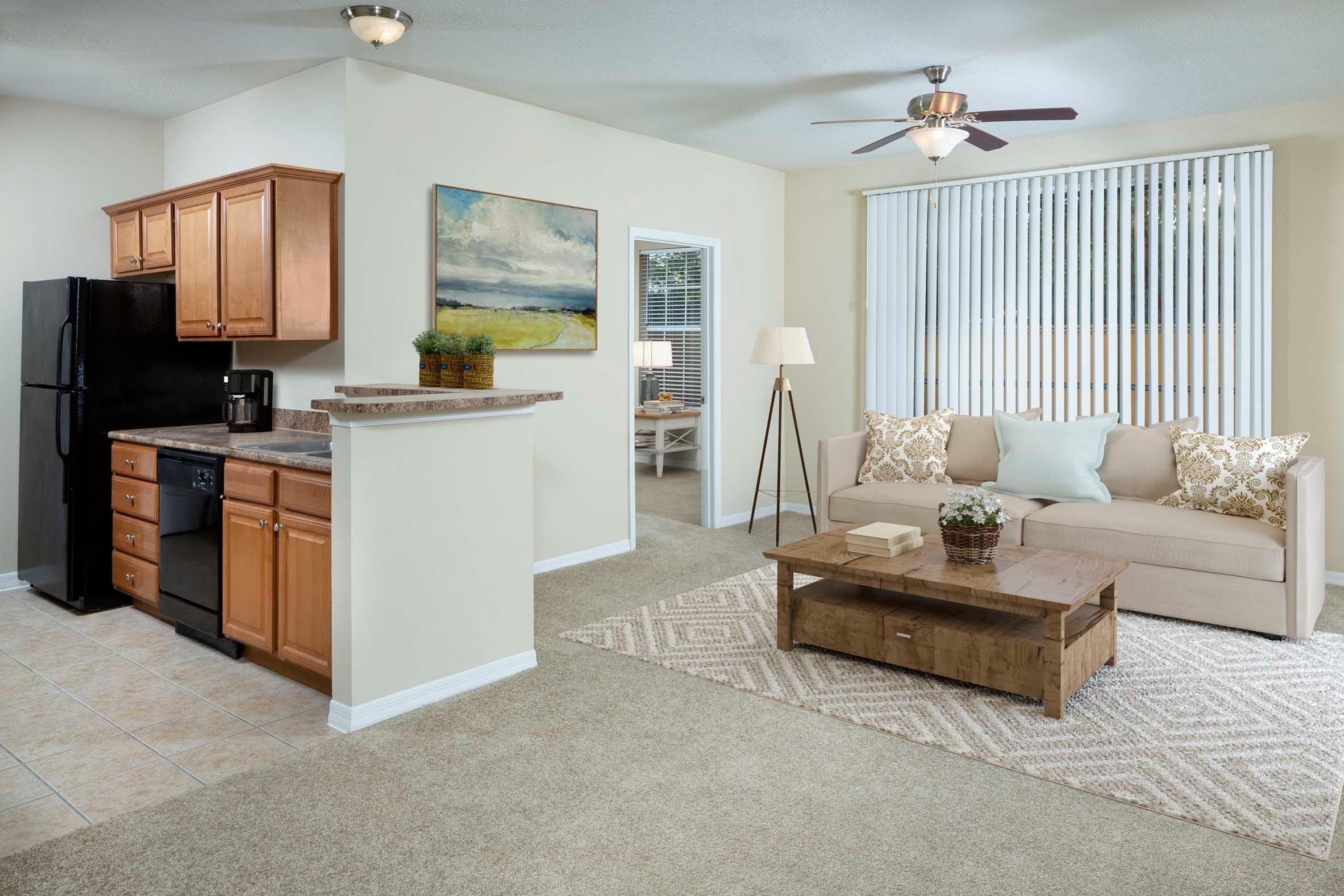 Kitchen and living room with ceiling fan vertical blinds and carpet flooring